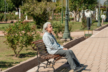 Fototapeta premium An 85 year old grandmother enjoys a peaceful moment sitting on a park bench