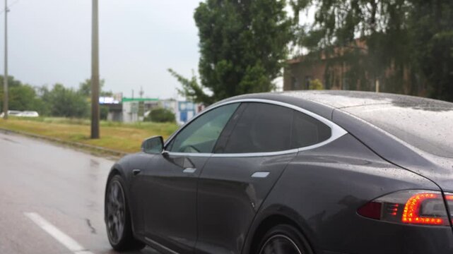 Ecology friendly car driving at urban road on sunny rainy day. Modern electrical automobile riding moving along motorway. Electric vehicle riding through empty highway. Concept of green innovation