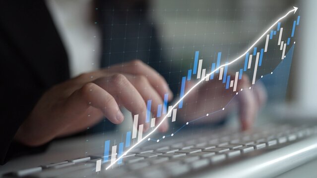 A professional analyzing data trends with hands typing on a keyboard while a financial graph displays a growth trajectory in a modern office setting. Copula