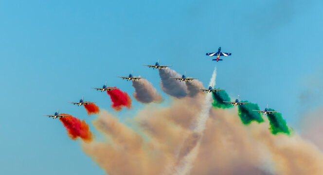 Aerobatic team Frecce Tricolori of the Italian Air Force, National Aerobatic Team. Airshow performance with aircraft, flight of pilotage team with colorful smoke trails. Planes and jets in the air.