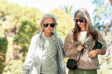 Fototapeta premium An 85 year old grandmother and her daughter enjoy a walk together in a sunny park