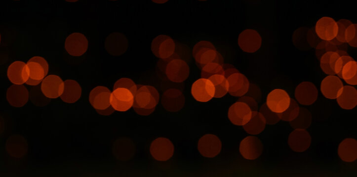 Abstract orange bokeh lights on a black background.