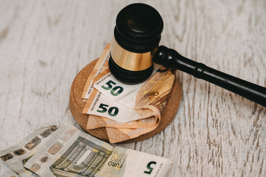 Judge's gavel on top of Euro banknotes on wooden background.Wooden gavel and cash money, concept of corruption and legal fees. Close-up of auction hammer and Euro bills, financial law concept