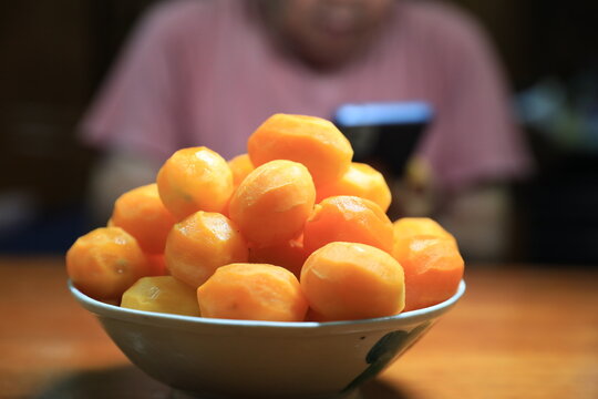 Fresh peeled Thai marian plums, also known as mayongchid or maprang, arranged in a white bowl on a wooden table. 