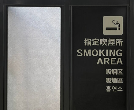 Smoking area sign with multilingual text in urban public space, Japan