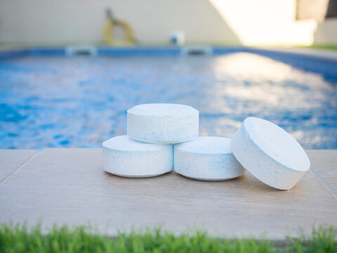 Close-up of chlorine tablets placed near a swimming pool, used for water sanitation and maintenance to keep pool clean and safe - pool maintenance concept