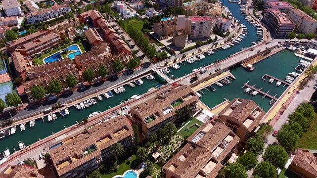 Overhead view of Xabia marina channels in Costa Blanca, Spain, showing moored boats along green waterways, residential buildings, bridges and swimming pools