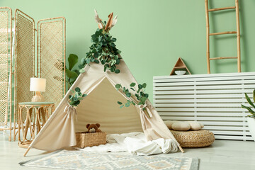 Cute wigwam with leaves and blanket in stylish child's room. Space for text © New Africa