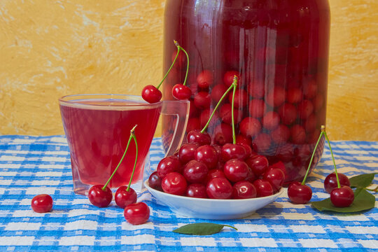 Homemade sour cherry compote in a glass jar with fresh cherries, canned cherry compote and freshly picked cherries