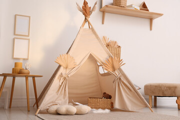 Stylish wigwam with dry leaves in child's room © New Africa