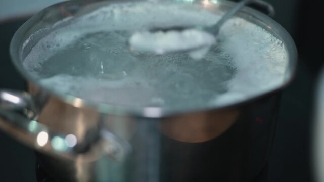 Water is boiling in a pot on a stove as another ingredient is prepared. This example shows how to combine items in cooking with a focus on a kitchen activity