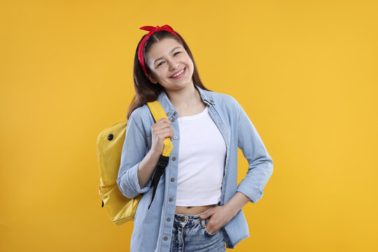 Teenage girl with backpack on orange background
