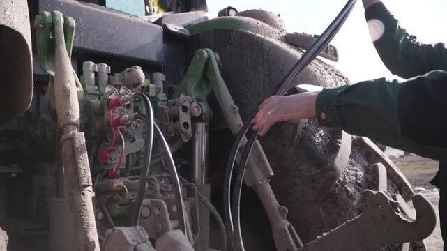 Farmer Connecting Grader Hydraulics to Tractor. Close view of farmer connecting hydraulic lines from grader to tractor