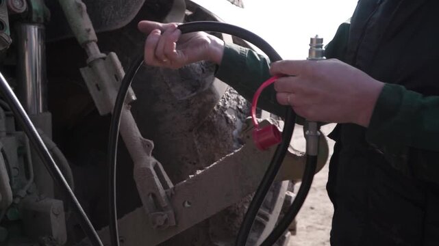 Farmer Connecting Grader Hydraulics to Tractor. Close view of farmer connecting hydraulic lines from grader to tractor