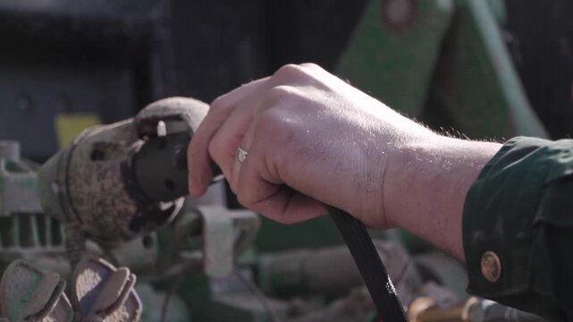 Farmer Connecting Grader Hydraulics to Tractor. Close view of farmer connecting hydraulic lines from grader to tractor