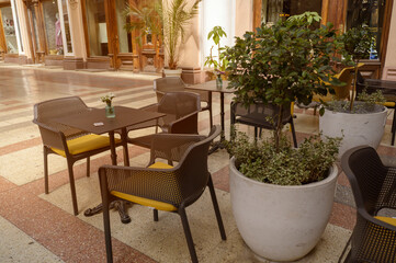 Obraz premium Coastal cafe terrace view featuring white chairs and tables in a park. Paved walkway nearby