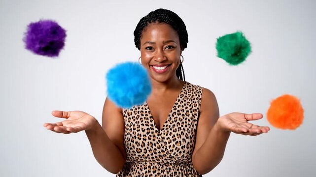 Happy Black woman juggling colorful pom poms in studio