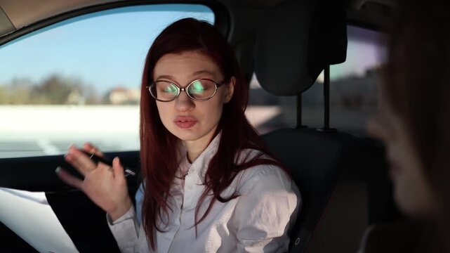 Driving instructor reviews notes and gives feedback to student inside car focused explanation with gestures clarifying mistakes and guiding next steps during practical lesson