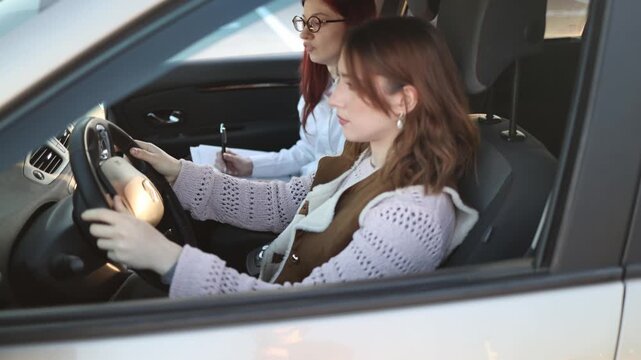 Careful young woman adjusting grip on steering wheel during driving lesson slight tension in posture while instructor reviews notes quiet moment of concentration before next move