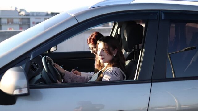 Woman drives car during practical lesson with instructor beside her focusing on steering control and road awareness gaining confidence behind the wheel in calm urban parking setting