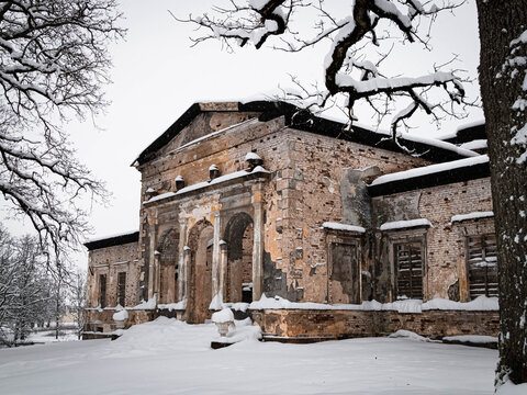 Abandoned manor outbuilding with classical facade in winter