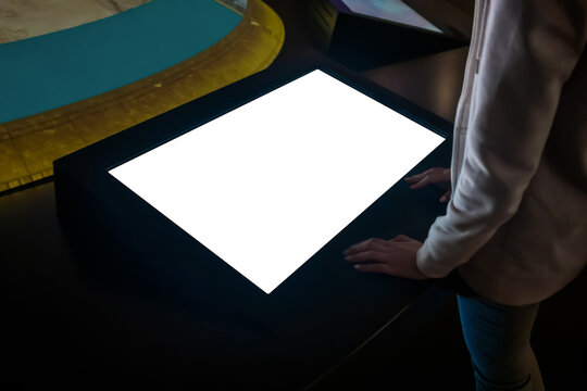 Mock up, copyspace, template, white screen, futuristic concept. Mockup: woman looking at blank white interactive touchscreen display of electronic kiosk in dark room of exhibition, museum