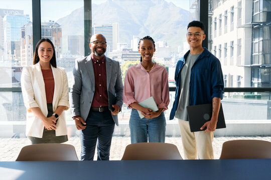 Happy diverse business team standing together in boardroom with city view during daytime