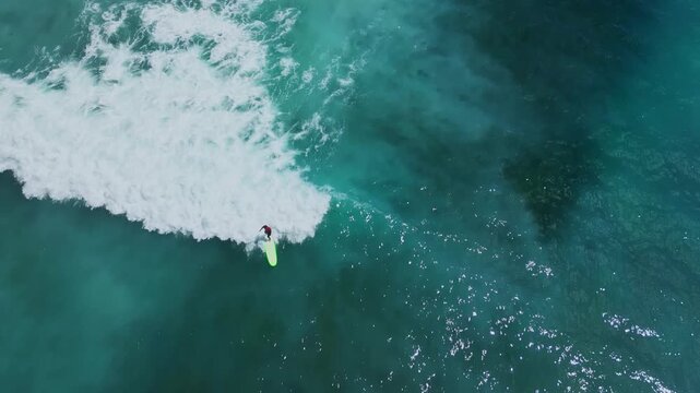Aerial Shot Of Surfer Carving Turquoise Face. Dynamic Aerial View Of Surfer Maneuvering On Bright Red Board. Dramatic Drone Footage Showing Surfer Executing Sharp Turn Near Reef Obstacle, Java island