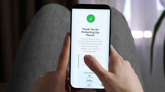 Showcase corporate social responsibility with this high-quality POV. User views a 60 dollars climate donation receipt on a smartphone. Features impact metrics like trees planted and CO2 reduction