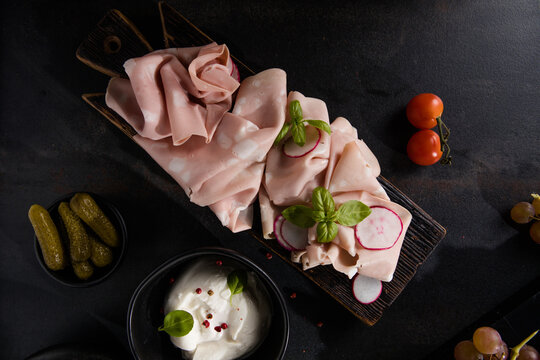 Slices Of Traditional Italian antipasti mortadella Bolognese on a wooden cutting board.