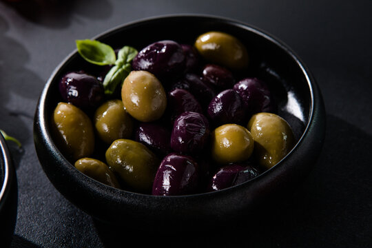 Olives calamata in a ceramic bowl on a black  background.