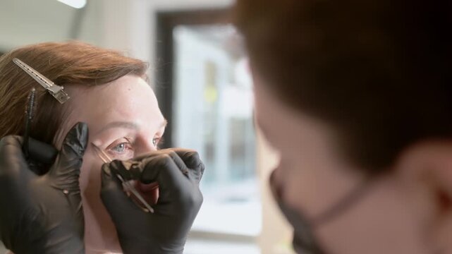 Professional eyebrow shaping and correction. An attractive mature woman receives a facial treatment and makeup application at a beauty salon. Perfect architecture eyebrows.