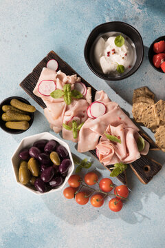 Slices Of Traditional Italian antipasti mortadella Bolognese on a wooden cutting board.