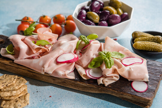 Slices Of Traditional Italian antipasti mortadella Bolognese on a wooden cutting board.