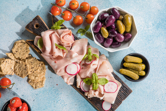 Slices Of Traditional Italian antipasti mortadella Bolognese on a wooden cutting board.