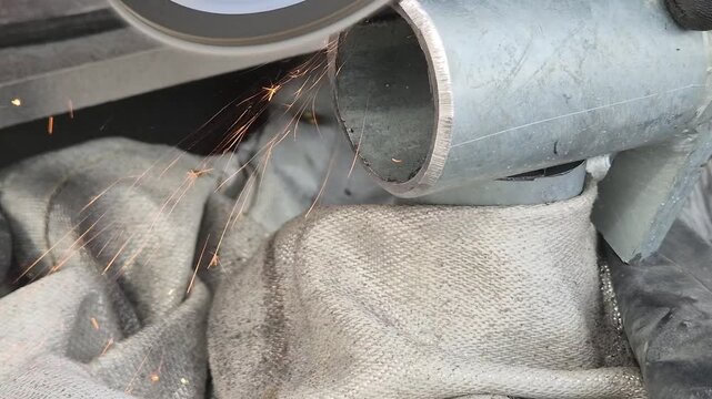 Sanding the bottom mounting bracket of a metal handrail using a handheld angle grinder.