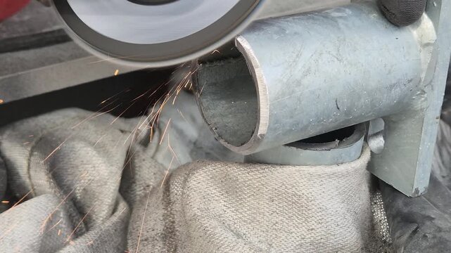 Slow motion close-up of an angle grinder finishing a handrail mounting base with sparks.