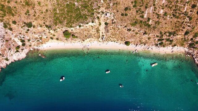 Aerial top down view of Nugal Beach near Makarska, Croatia, with crystal clear turquoise water of the Adriatic Sea and boats anchored near the rocky coastline