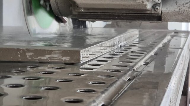 Slow motion low angle shot of water splashing while cutting a floor tile with a wet saw.