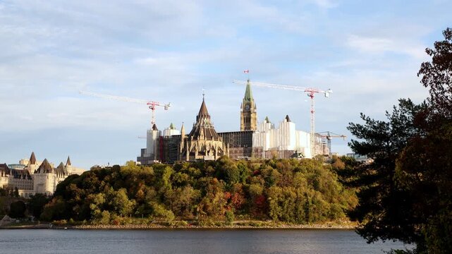 Parliament Hill across Ottawa River. Canadian government buildings under renovation in autumn landscape