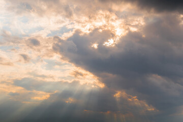 Fototapeta premium View of sun beams are shining through dramatic rain clouds - warm sunrise or sunset illumination, sun lens flare. Peaceful, hope, religion, spiritual and nature concept