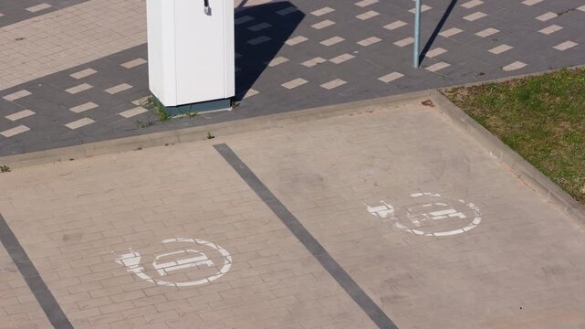 Urban parking spots. Scene depicting reserved electric parking with markings and shadows. Commercial urban scene showing unused electric parking bays with detailed stencil symbols and textures