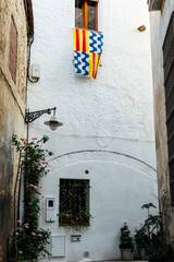 Fototapeta premium Street of the old quarter of Badalona with a lamppost and flag of the city in a window