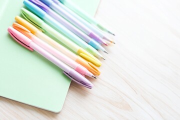 Obraz premium Writing Tools Arranged on a Green Notebook on a Wooden Table With Natural Light Coming In