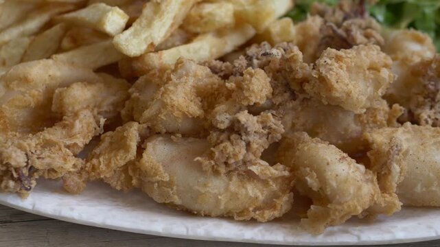Golden seafood highlights crispy texture and appetizing presentation. Calamari popular in Mediterranean restaurants and tourism food promotion. Squid dish used in menu design and advertising campaigns