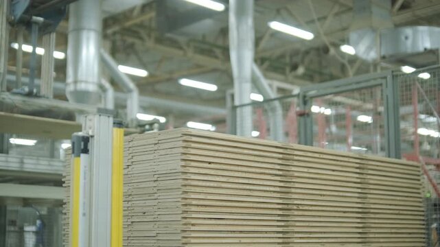 Detailed close-up of a massive stack of thin wooden slats or plywood sheets prepared for parquet production. The texture of light natural wood fills the frame in a professional woodworking warehouse
