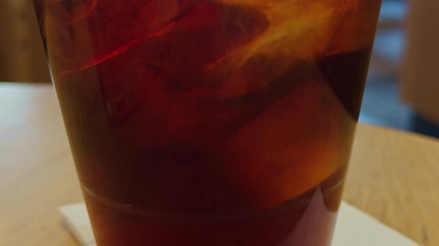 Frozen beverage moisture. Icy drink displayed in transparent cup with frost and shimmering condensation. Frosty beverage served in disposable cup highlighting icy textures and high contrast visuals