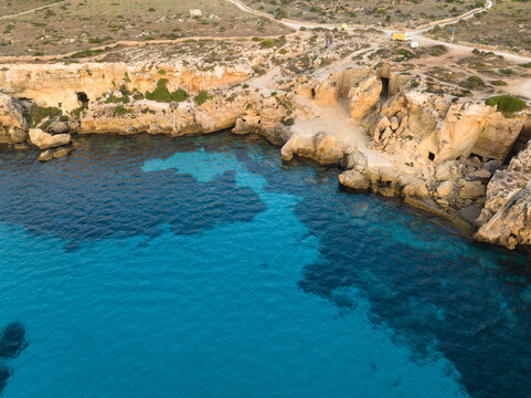 Aerial view of Bue Marino Beach with its crystal clear turquoise waters, rugged limestone cliffs, and ancient coastal caves in Sicily, Italy.