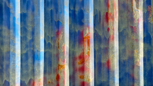 Grungy blue shipping container surface with red and yellow paint drips and rust