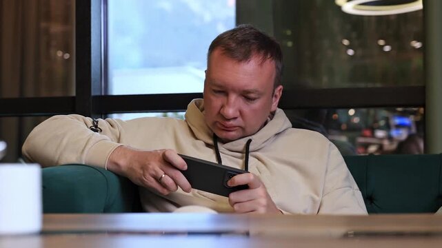 A man plays a game on a smartphone.